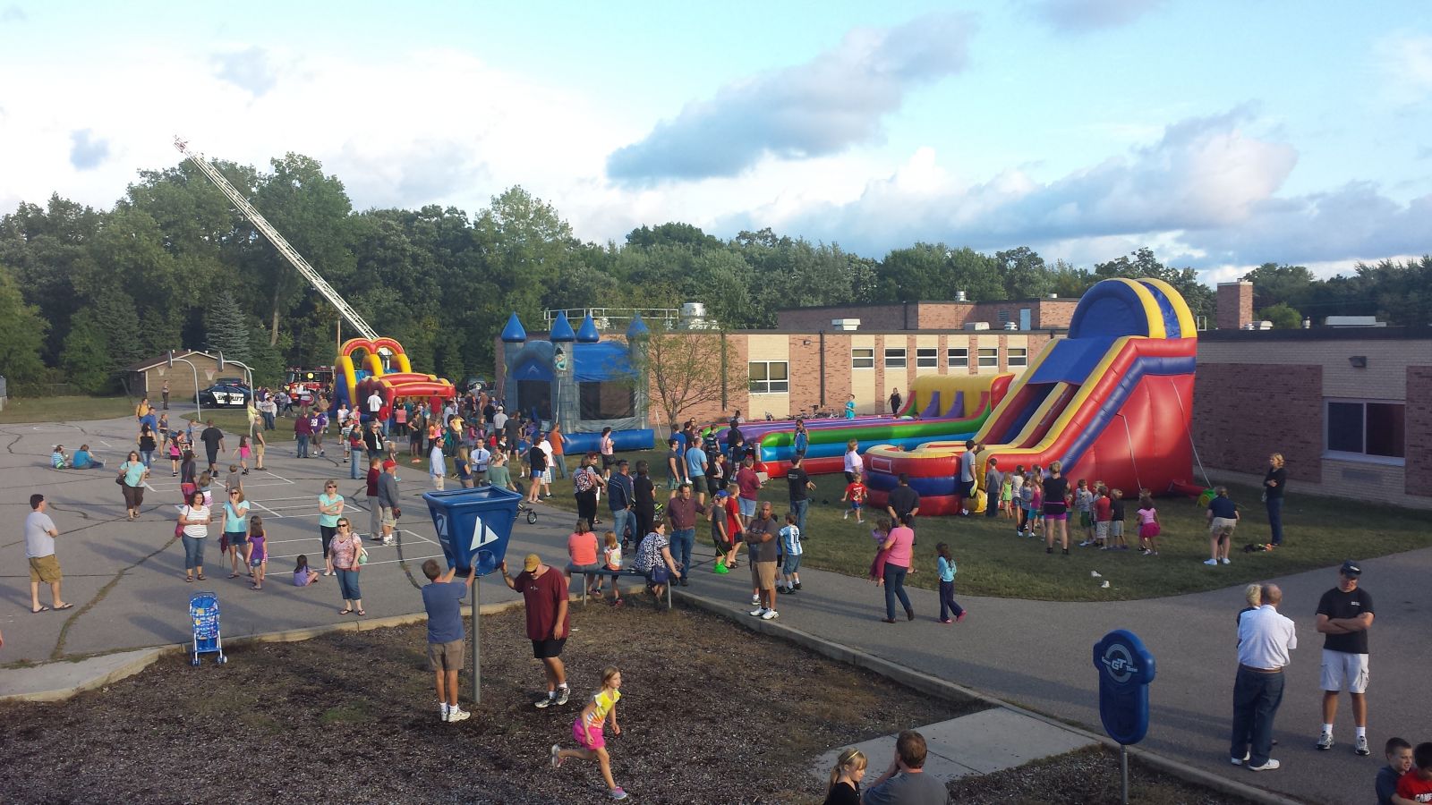 School carnival with giant slide, bounce house, obstacle course, and other inflatables